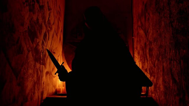 A Man Occultist In Black Robes Stands With A Knife In His Hands