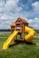 Wooden playground with yellow slides on a green meadow 