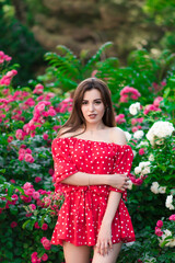 A beautiful girl in a red dress walks in the park, posing in a dress. Fashion concept 