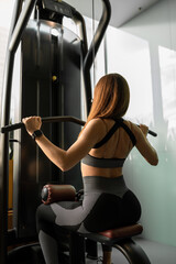 A woman in sports leggings is engaged in the simulator. Beauty, sports, fitness and youth