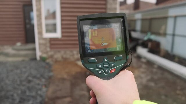 Close-up of a builder analyzing heat on a wall with a building thermal imager. Inspection of structures  