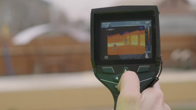 Close-up of a builder analyzing heat on a wall with a building thermal imager. Inspection of structures  