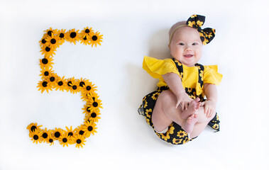 5 month old baby girl in a dress with the flowers. Baby milestone five months.	 - Powered by Adobe