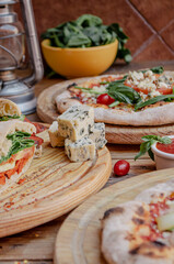 blue cheese, bread, tomatoes, artisan pizza and vegetables in a wooden table ready to eat