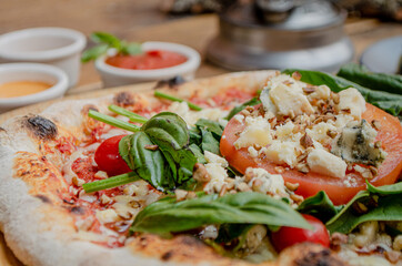 Fototapeta na wymiar Artisan pizza with tomato, chesse and arugula on a wooden table