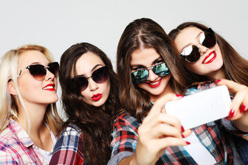Obraz premium four happy teenage girls with smartphone taking selfie