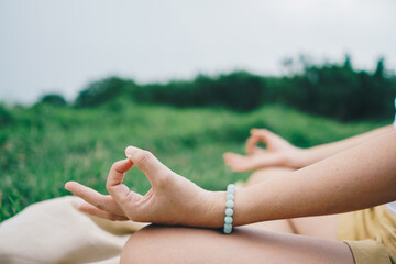 Woman practicing yoga lesson, breathing, meditating exercise, outdoor in grass field. Well being, wellness.