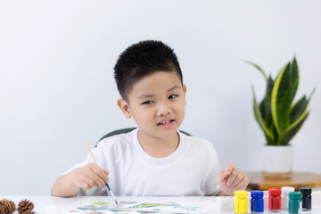 Happy little Asian kid at the table draw with water color Learning and education of kid.