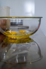Blurry photo of a Yellow egg yolks in a clear transparent bowl.