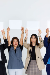 Fototapeta na wymiar Studio shot group of female office staff in business wears stand hold blank empty paper sign cover face for advertisement text on white background