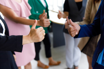 Unrecognizable unidentified female officer staff in business suit show thumb up while others standing ovation side by side applauding hands showing warm greeting celebration in blurred background
