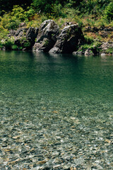 The crystal blue waters of a river flow over smooth rocks.