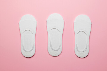 Three pairs of packed women's white short socks on a pink background.
