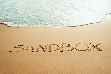 Sandbox text written in the sand on the beach in Phuket, Thailand with incoming wave