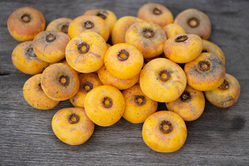 Diospyros decandra Lour fruit ( Ebenaceae ) gold apple ,fruit and herb on wooden table