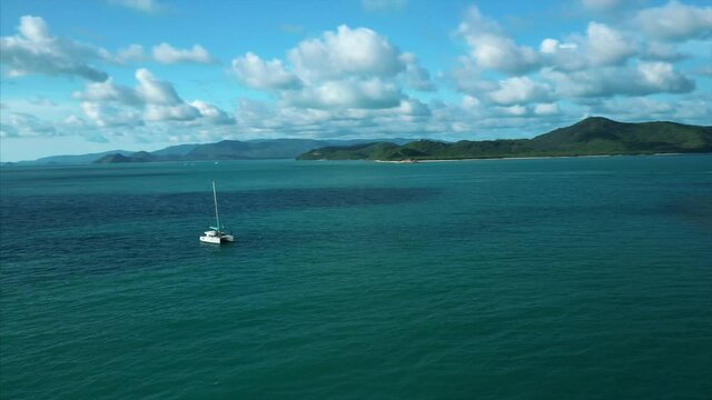 Drone tracks Catamaran in exotic island destination. 