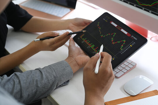 Cropped shot two business people checking stock market on desktop digital tablet together.