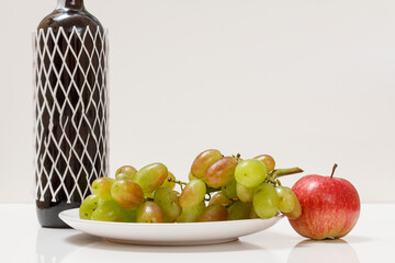 Bottle of wine with green grapes and apple.