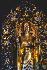 Beautiful details of a golden standing buddha sculpture at a buddhist temple in Kamakura, Japan