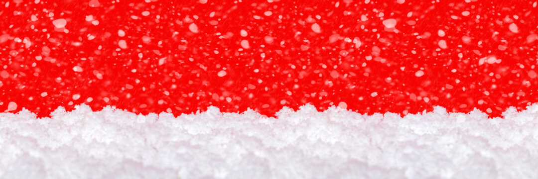 Snow on a red background. Falling snow. Christmas theme, large format, panoramic photo for a banner or website header. Christmas greeting card for printing.