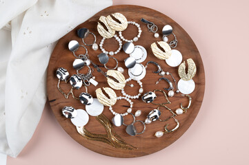 Trendy stylish bijouterie set on white cloth and wooden display. Jewelry with pearl