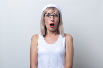 Shocked young woman in a white hat and glasses on a light background