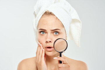 pretty woman with towel on head face close up dermatology magnifier near face
