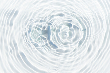 Water droplets fall on the transparent surface of the water in sunlight. Top view, flat lay