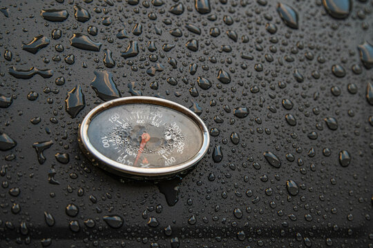 Close-up shot of a gauge on a black wet surface during the rain