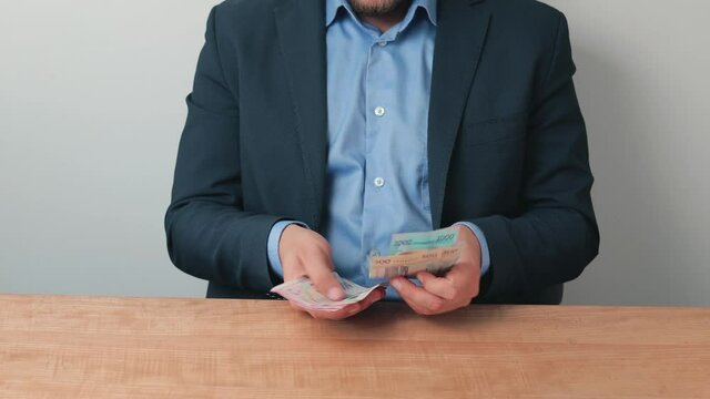 Business person counting ukrainian hryvnia banknotes on the table, paying cash. Concept of investment, success or corruption and bribery