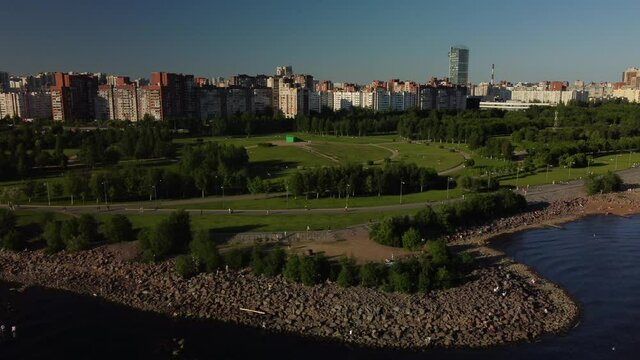 Drone flight over the city beach on a sunny day, where many people are resting. Flight over the park of the 300th anniversary. Saint Petersburg, Russia