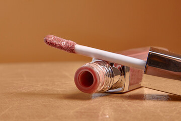 Liquid lipstick and applicator on  color background. Open tube of lip gloss and wand brush with makeup product on pastel surface. copy space