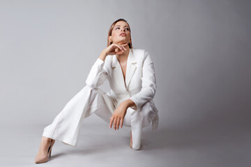 Young stylish lady in a white pantsuit, portrait in the studio.