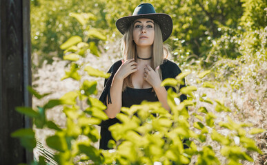 Girl in American country style black boho jacket with a fringe and cowboy hat at nature