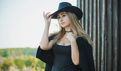 Girl in American country style black boho jacket with a fringe and cowboy hat at nature