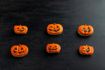 Orange ginger cookies for Halloween in the form of a pumpkin lies horizontally on a dark table. Smiling cookie. Top view