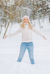 Fototapeta na wymiar Pretty girl in a Winter Suede Lambs Wool Jacket enjoying winter moments. Outdoors photo of blonde in a pink hat having fun on a snowy morning on a blurred nature background.