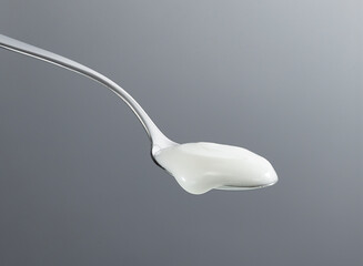 Spoon scooping yogurt isolated on gray background