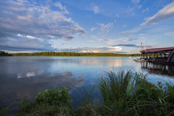 Cloudy sky over the river in the evening. Picturesque landscape with clouds and a river. Bright green grass in the foreground.