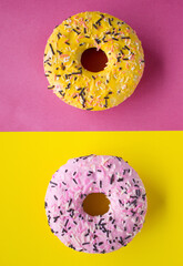 Tasty pink and yellow donuts on colourful background in pop art style. Top view, vertical image