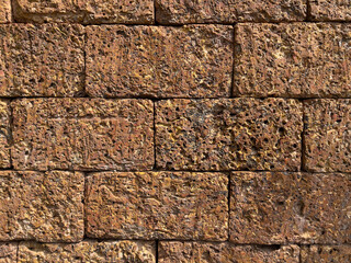 Laterite brick wall background and texture. Natural Laterite rock for outdoor and tropical garden or Bali garden wall decoration. Selective focus