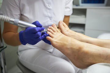 Obraz premium Peeling feet Pedicure SPA procedure in the beauty salon. Electric apparatus for pedicure. Woman getting her feet peeled in spa center