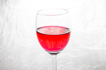 Glass of red  wine on a white crumpled paper background.