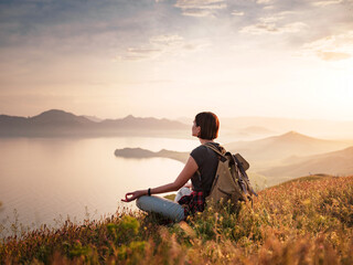 A young Asian woman with a backpack hiking in the summer.
