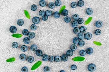 Blueberries and green leaves on concrete background with place for text