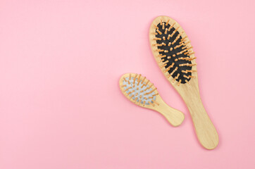 Two wooden hairbrushes on a pink background with place for text. Eco-friendly hair combs. Hair care with natural accessories. Zero waste, no plastic