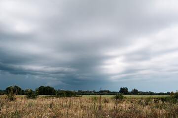 Gray wave rain clouds in front of a field