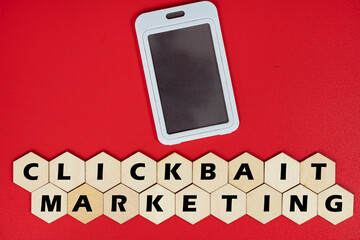 Mobile phone replica with wooden hexagon tiles and text Clickbait Marketing. Clickbait is a method to entice user to click a post in the internet