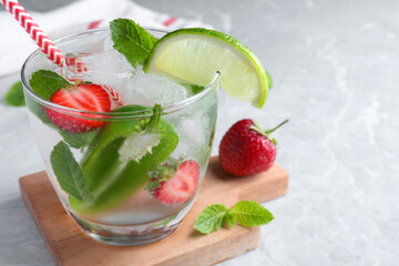 Spicy cocktail with jalapeno, strawberry, lime and mint on light grey table. Space for text