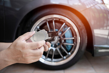 Car maintenance concept : Close up hand a man hold plate lock of brake pad and brake pad in service...